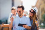 Smiling parents and little girl with tablet pc and credit card outdoor